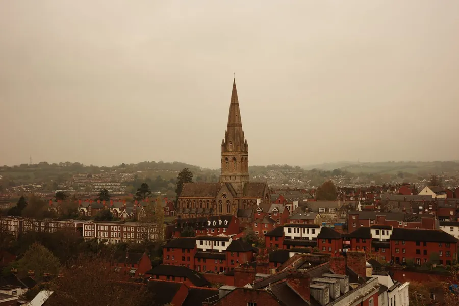 A stone church spire standing above red brick rooftops in an English market town, the kind of roofscape West Lancashire protects in Ormskirk's conservation area
