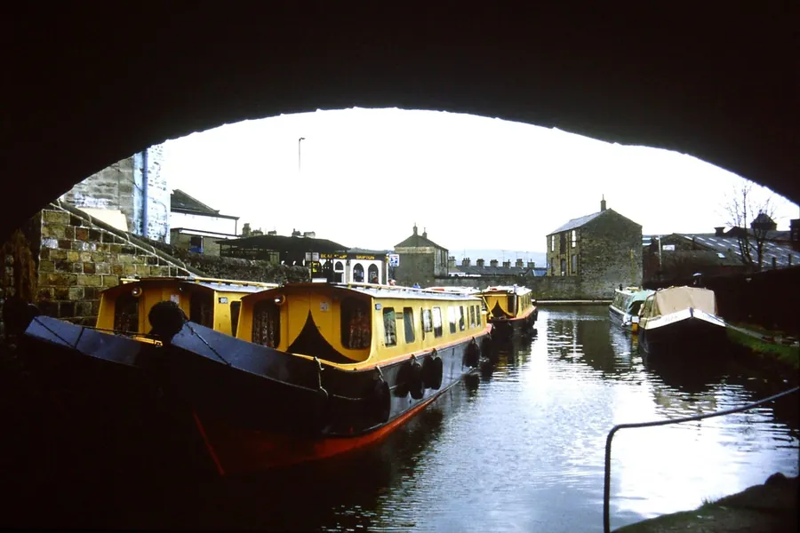 Narrowboats moored beneath a stone bridge on the Leeds and Liverpool Canal, the waterway that runs through the heart of Burscough
