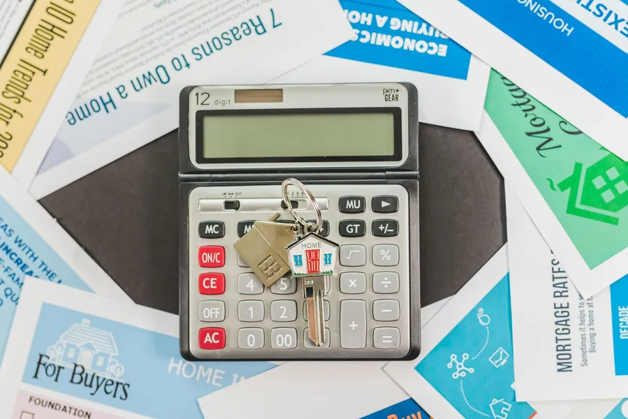 Mortgage paperwork, a calculator and house keys laid out on a desk
