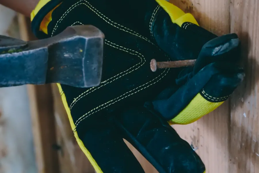 Gloved hands driving a fixing into a timber roof batten during a mechanical re-fix in Southport