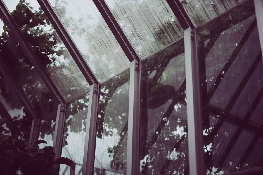 Rain running down a tired conservatory roof and its glazing bars, the pattern seen on ageing Southport sun lounges