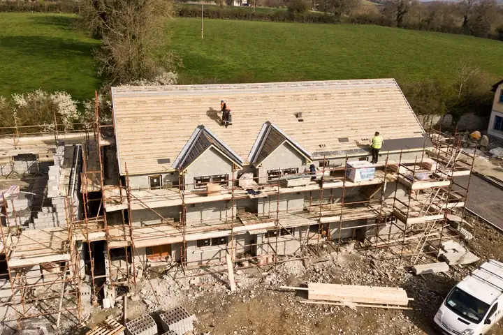 A house being re-roofed, seen from above with scaffold up and new covering going on