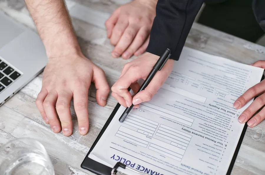 Homeowner and contractor reviewing a public liability insurance policy document before roof work