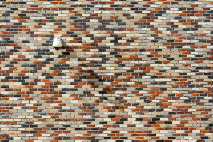 Security camera fixed to a brick wall, one of the deterrents that makes roof lead a less attractive target