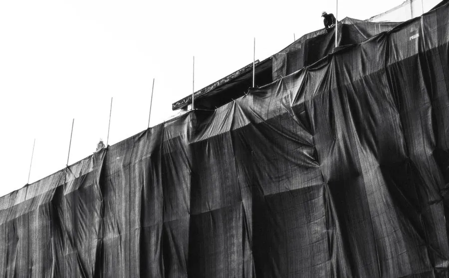Scaffolding wrapped in protective sheeting, which behaves like a sail in coastal wind
