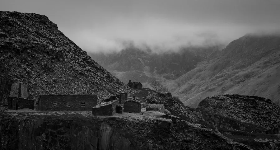 Abandoned workings and spoil runs of a Welsh slate quarry under low cloud, the origin and grade of natural slate a cheap Southport re-roof quote leaves unnamed