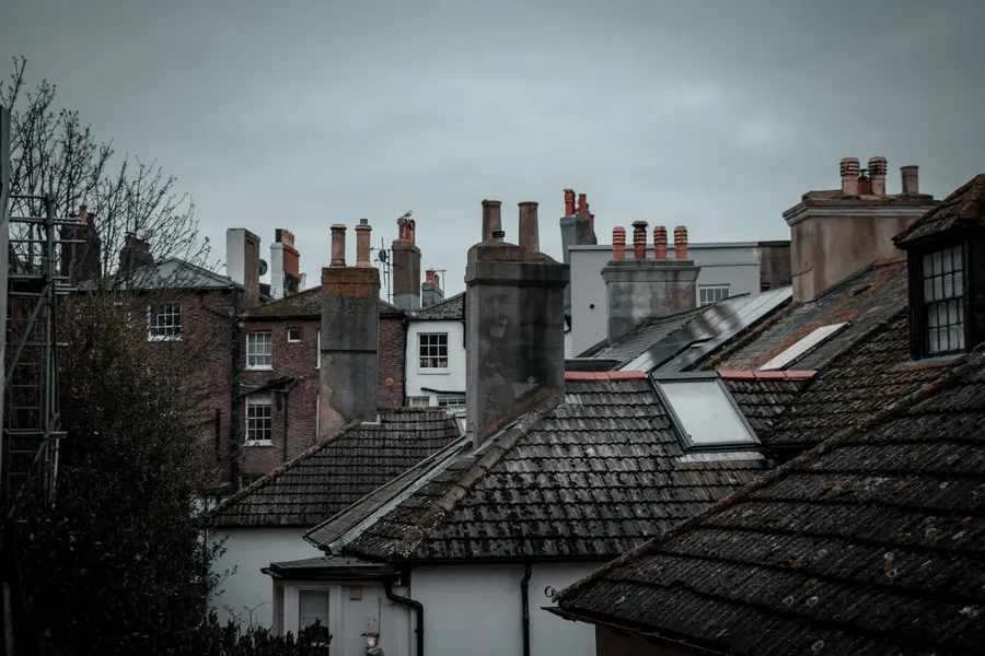 Grey winter light over slate roofs and chimney stacks, weather that slows roof work without stopping it