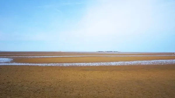 A vast flat sandy beach at low tide under a wide sky, as at Ainsdale-on-Sea