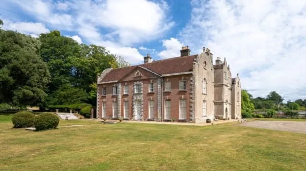 A handsome brick country house across its lawns, in the manner of Meols Hall at Churchtown