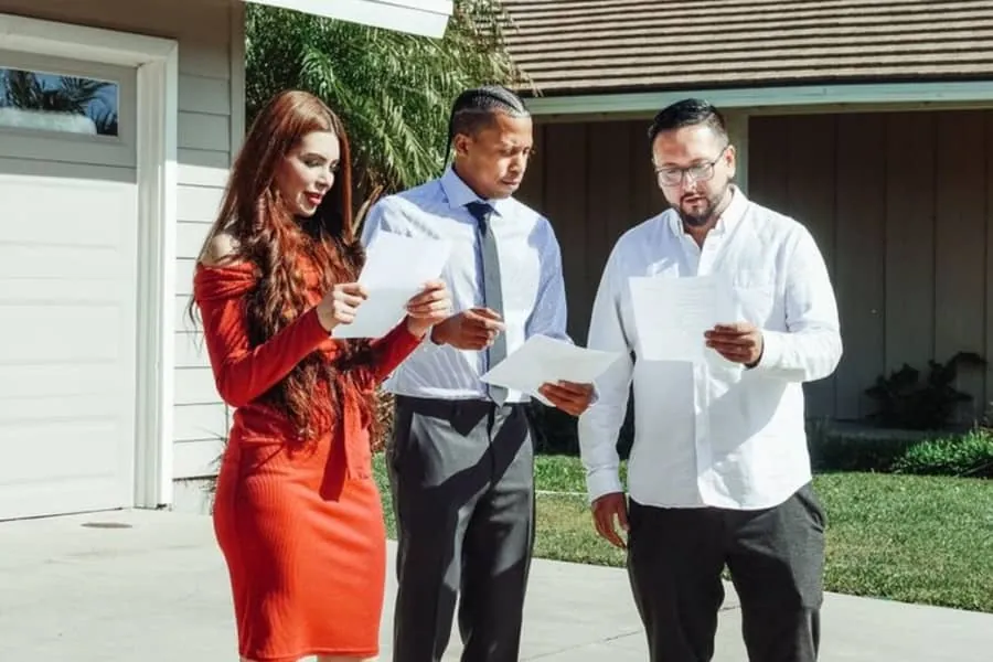 Homeowners going through paperwork outside a house before agreeing roofing work