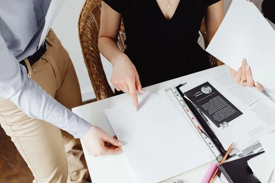 Two people comparing written quotes and paperwork side by side