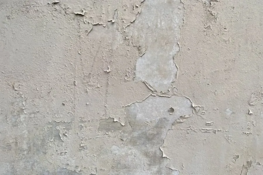 Peeling paint and blown plaster on an interior wall caused by long-term water ingress