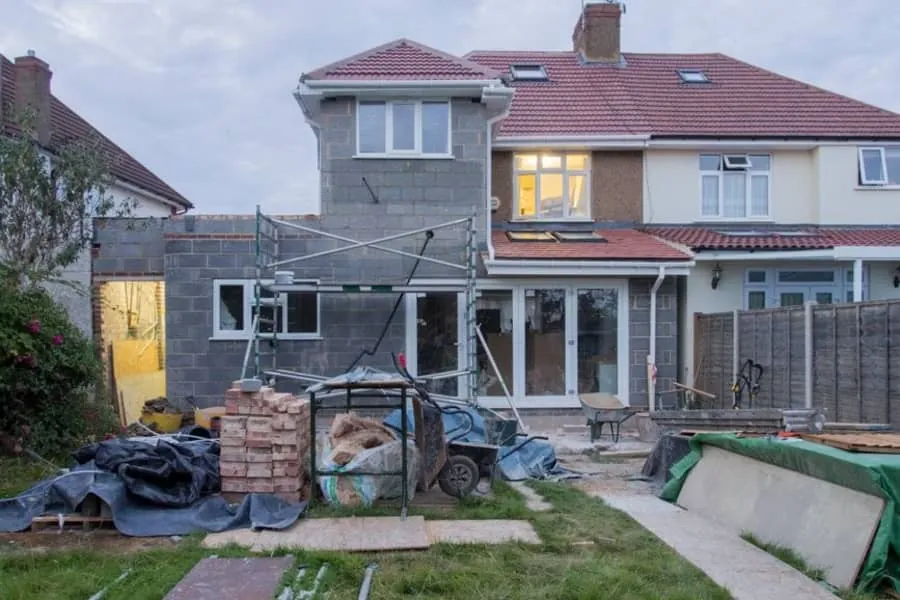 A rear extension under construction on a British semi-detached house with scaffolding in place