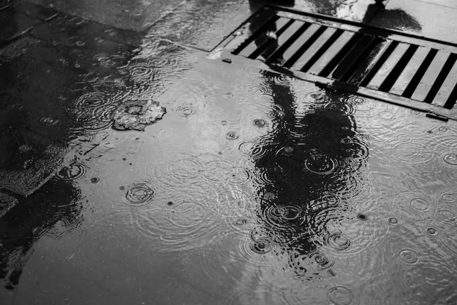 Rain falling into standing water beside a roof drainage outlet