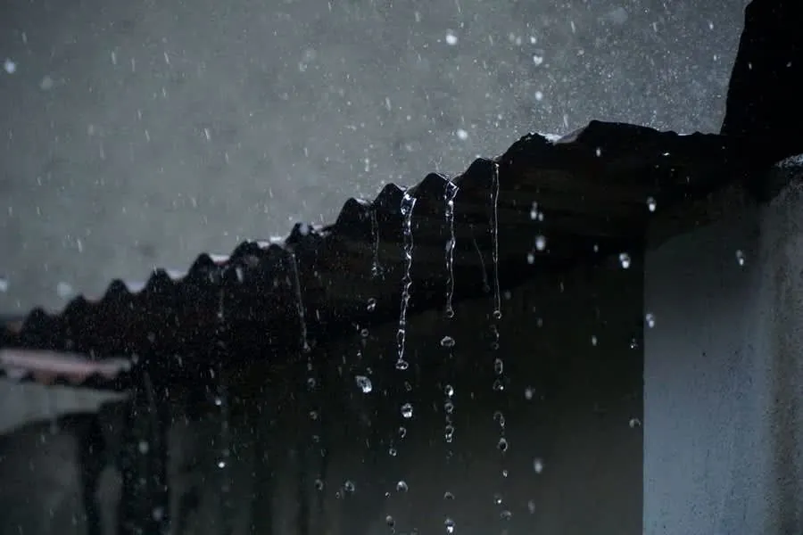 Rainwater running off the edge of a low roof during heavy rain