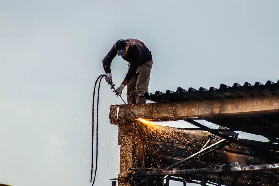A roofer using a gas torch to bond bitumen felt on a flat roof