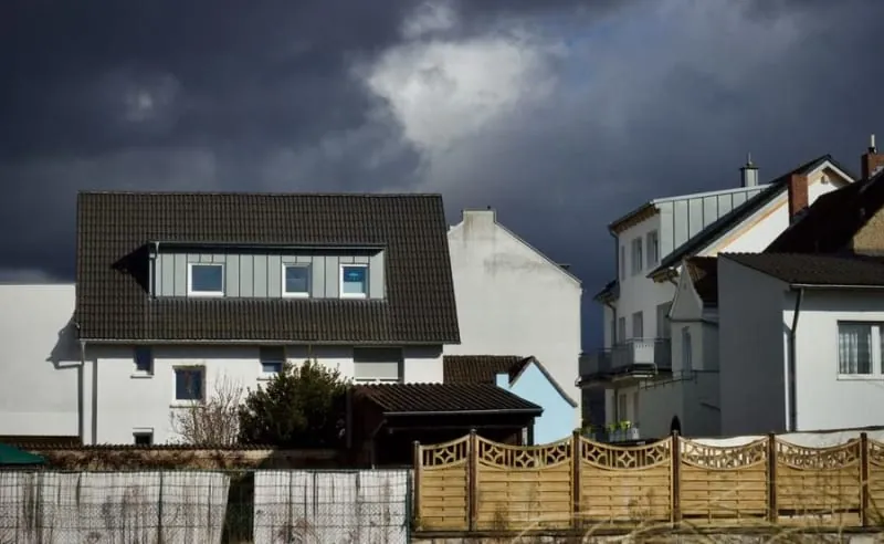 A dark stormy sky bearing down over houses on flat open land like the fields around Banks