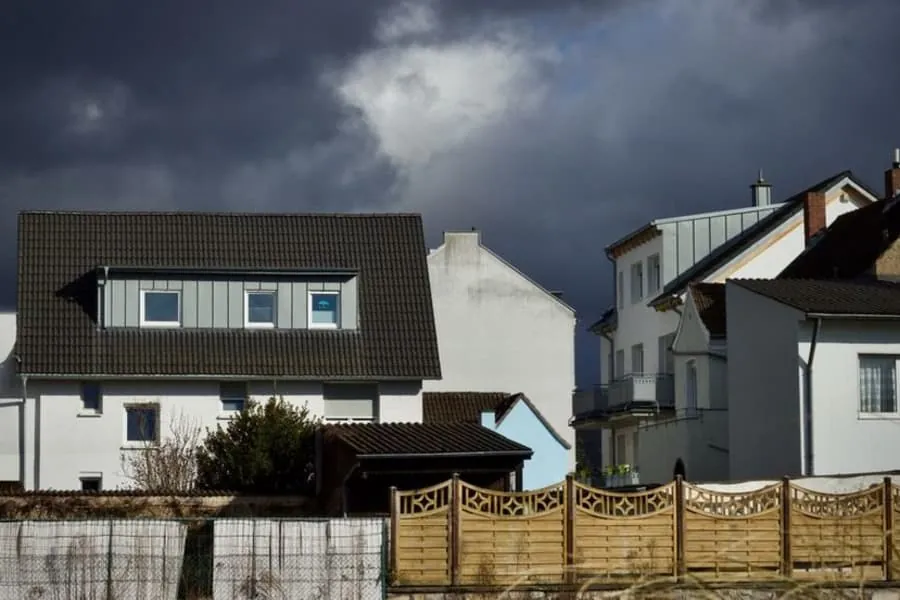 Suburban houses under a dark, dramatic sky before a storm