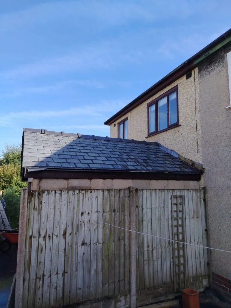 A newly slated lean-to roof meeting a rendered house wall, with a lead flashing dressed along the abutment
