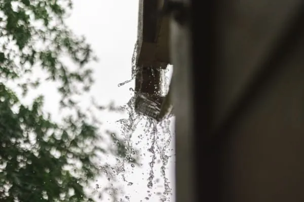 Rainwater pouring from a blocked gutter on a house in Southport