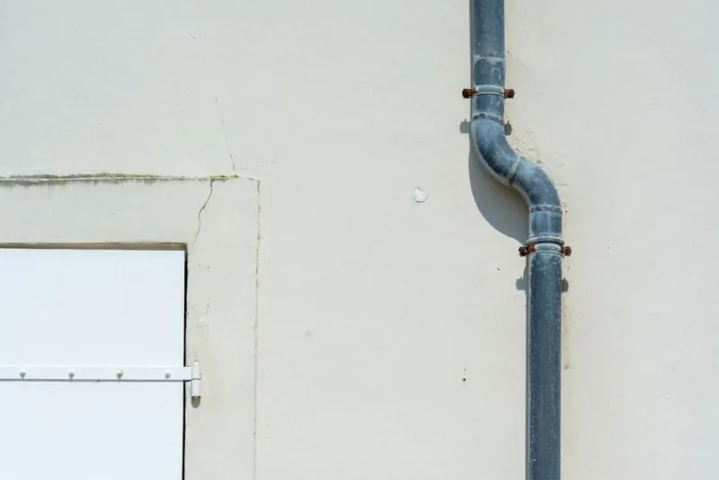 A gutter and downpipe on a brick wall, the long rainwater runs that Burscough's terraces depend on