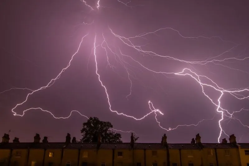 Lightning over rooftops in open country during the kind of storm that arrives off the Ribble at Banks